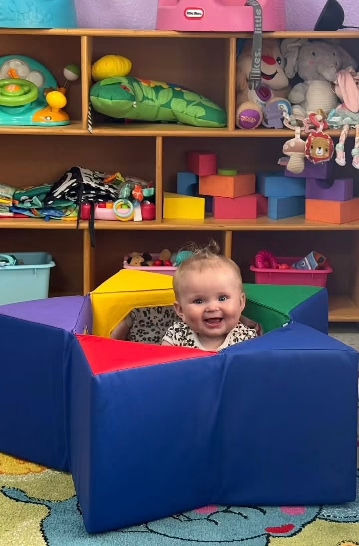 Smiling baby playing inside a soft foam block play area